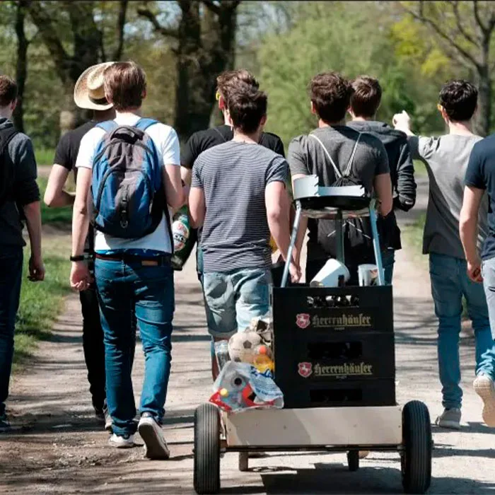 Grupo de hombres llevando un carro lleno de bebidas y una barbacoa