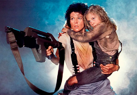 Fotografía de la teniente Ripley sujetando un arma en una mano y a Newt en la otra mano en la segunda película de Alien.