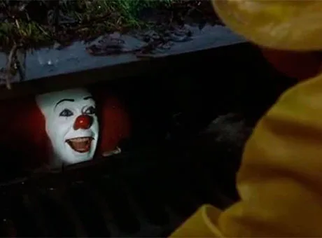 Pennywise asomándose por un hueco de una alcantarilla y hablando con Georgie en It
