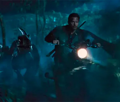 Owen Grady en moto junto a un velociraptor