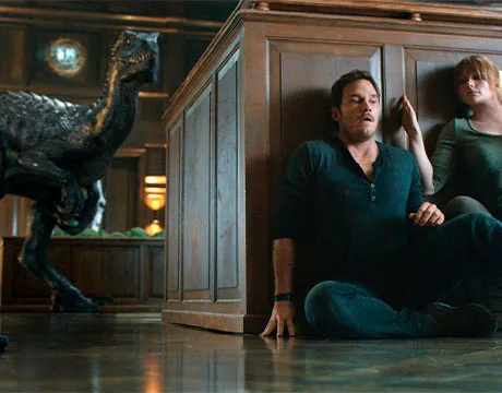 Owen y Claire escondiéndose detrás del Indoraptor