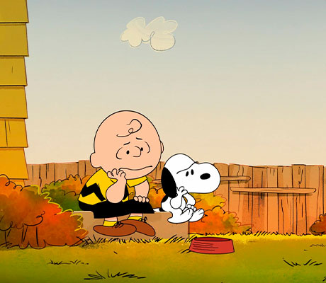 Charlie Brown sentado junto a Snoopy