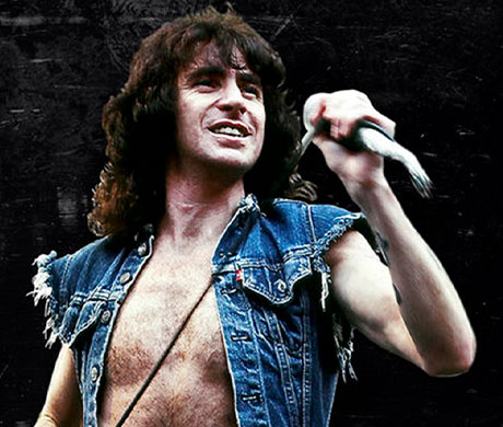 Fotografía de Bon Scott, tercer vocalista de la banda ACDC sujetando un micrófono.